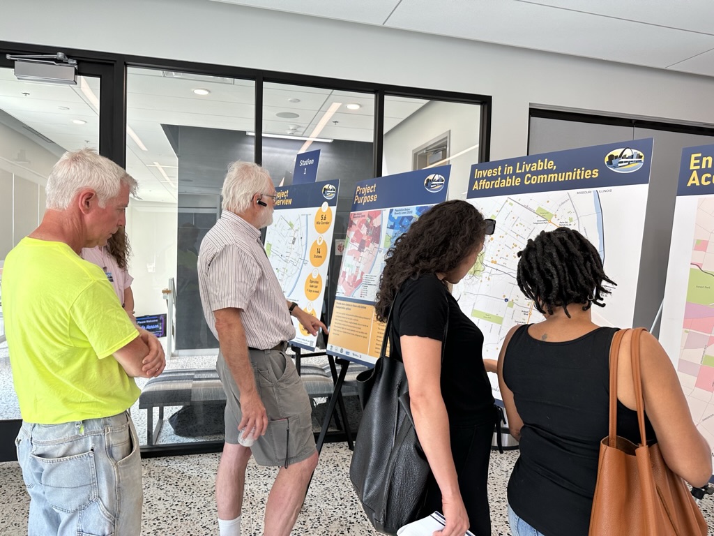 Two men and two women looking at public meeting boards.